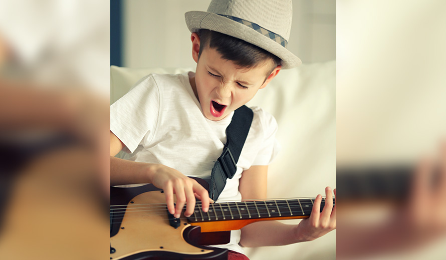 Niñito cantando y tocando la guitarra.