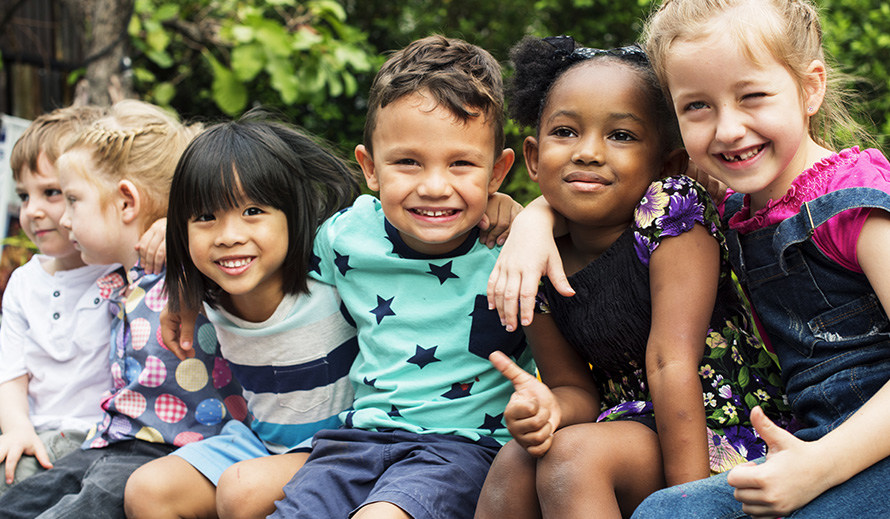 Smiling group of multiracial children, hugging.