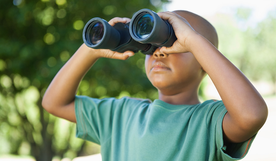 Niño mirando a través de binoculares. 