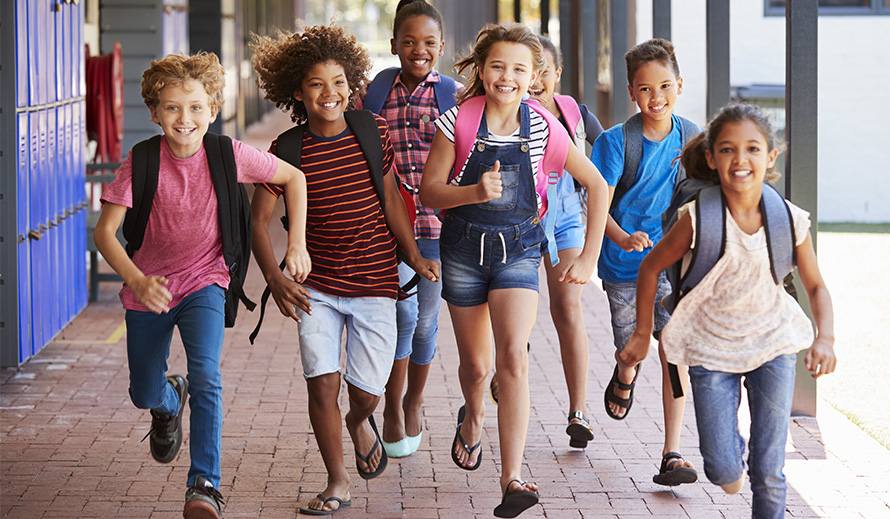 Niños felices corriendo por los pasillos de una escuela.