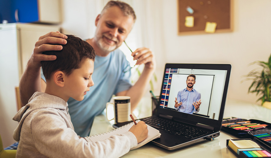 A father helps his son with his virtual studies. 