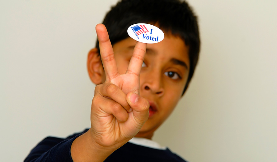 Boy holding up I voted sticker peace hand sign