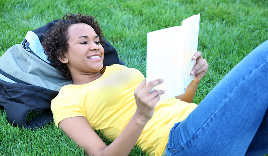 Jovencita adolescente felizmente leyendo un libro