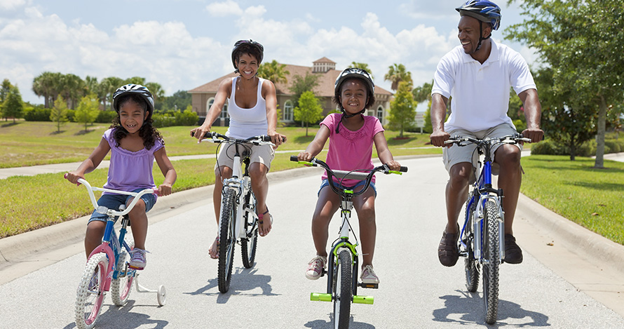 Una familia afroamericana da un paseo en bicicleta durante el verano.