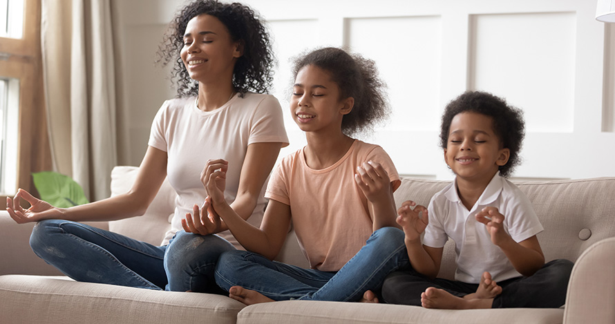 An African American mother meditates with her two young children.