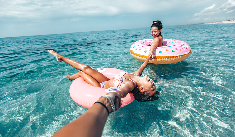 Two girls enjoy the water on floats. 