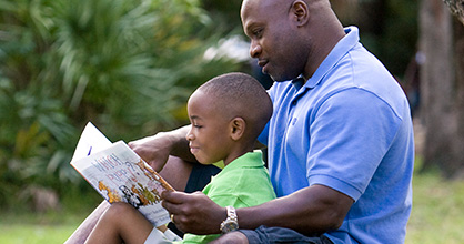 Padre leyendo un libro a su hijo en el parque