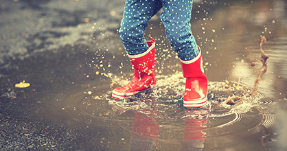 Botas de lluvia infantiles salpicando en un charco